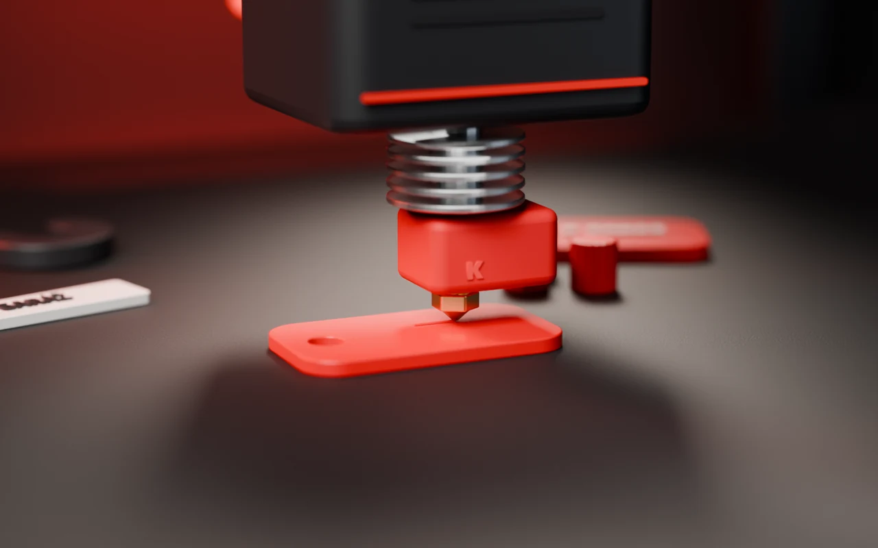 3D tiskárna tiskne červený přívěsek na klíče